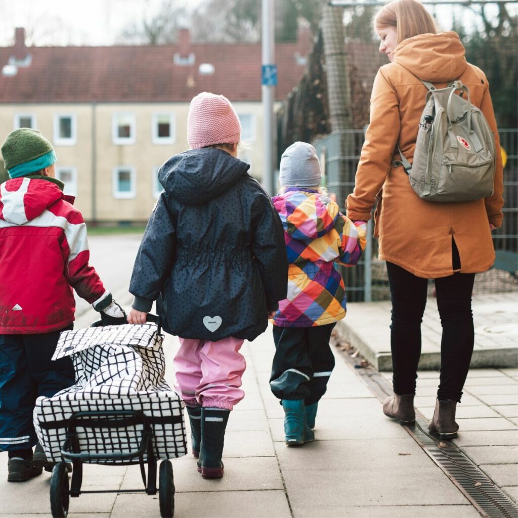 3 Kinder gehen mit Erzieherin einkaufen
